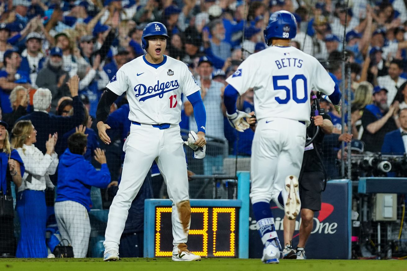 Shohei Ohtani #17 and Mookie Betts #50 of the Los Angeles Dodgers celebrate after Ohtani scored in the eighth inning of Game 1 of the 2024 World Series presented by Capital One between the New York Yankees and the Los Angeles Dodgers at Dodger Stadium on Friday, October 25, 2024 in Los Angeles, California.