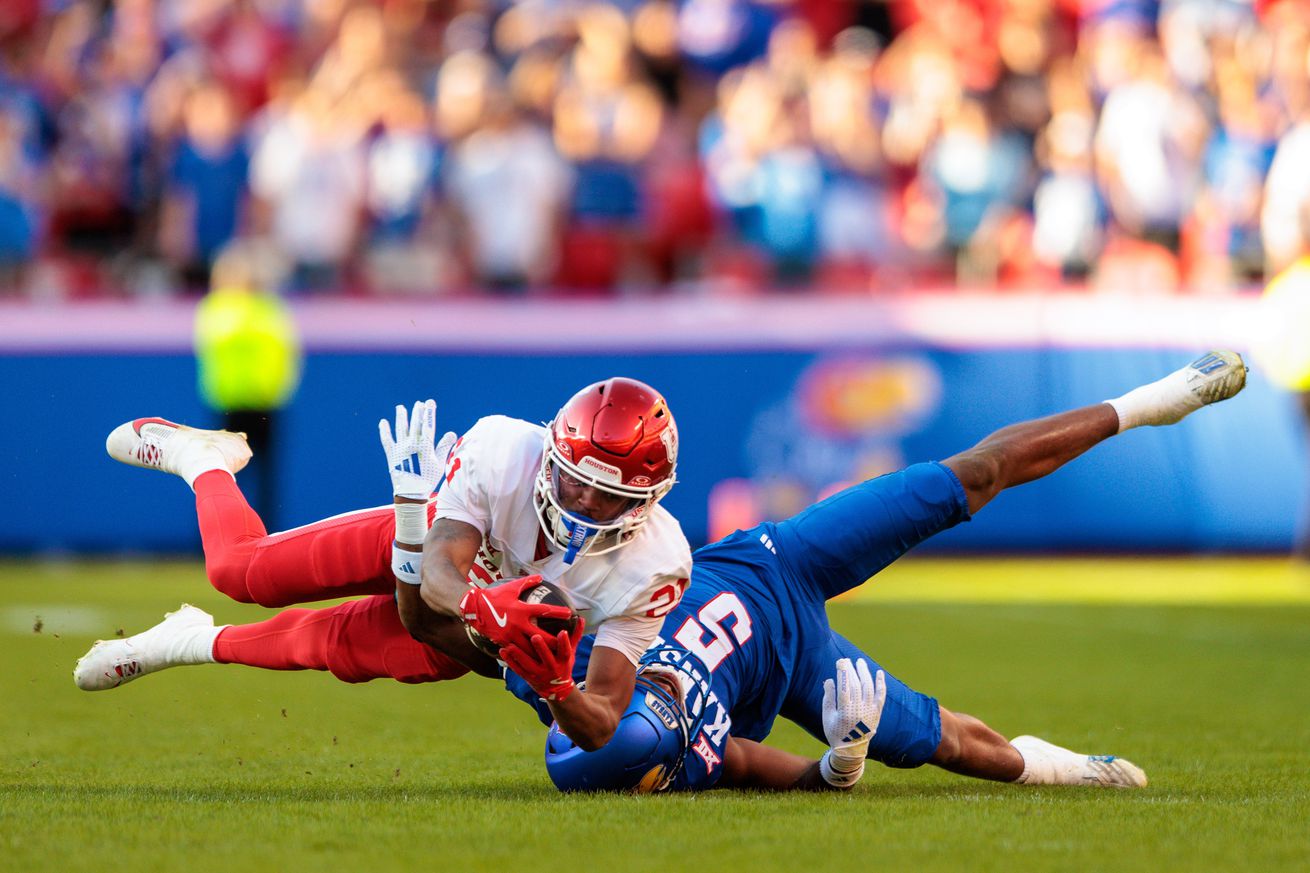 Oct 19, 2024; Kansas City, Missouri, USA; Houston Cougars running back Stacy Sneed (21) makes a reception over Kansas Jayhawks safety O.J. Burroughs (5) during the third quarter at GEHA Field at Arrowhead Stadium.