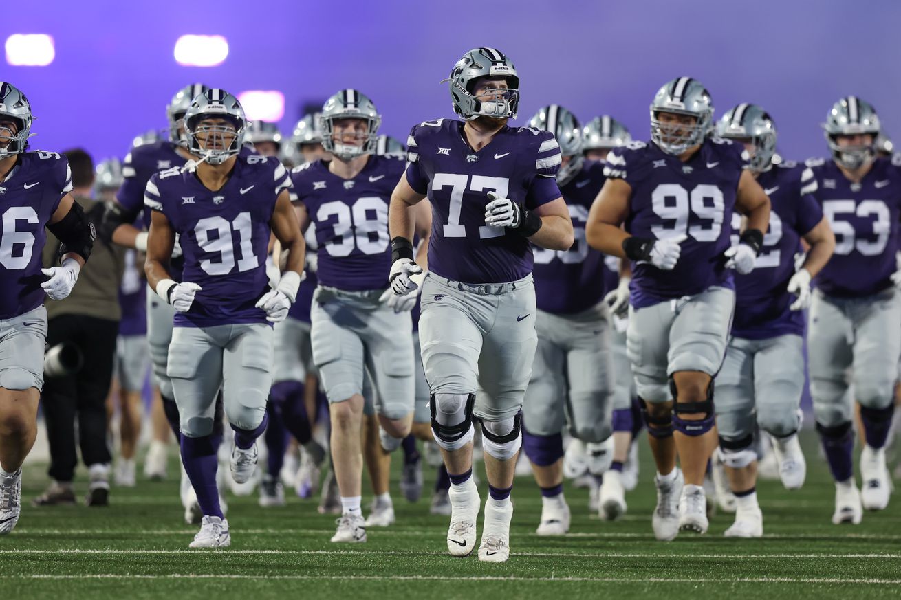 MANHATTAN, KS - NOVEMBER 16: Kansas State Wildcats offensive lineman Carver Willis (77) leads his team onto the field as purple smoke fills the air before a Big 12 game between the Arizona State Sun Devils and Kansas State Wildcats on November 16, 2024 at Bill Snyder Family Stadium in Manhattan, KS.