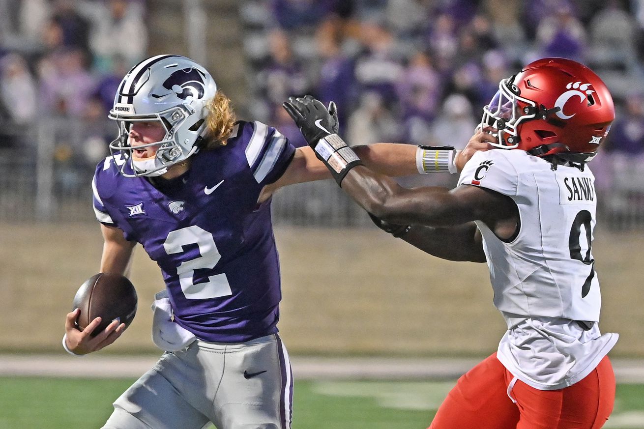 MANHATTAN, KS - NOVEMBER 23: Quarterback Avery Johnson #2 of the Kansas State Wildcats stiff-arms linebacker Jiquan Sanks #9 of the Cincinnati Bearcats in the first half at Bill Snyder Family Football Stadium on November 23, 2024 in Manhattan, Kansas.