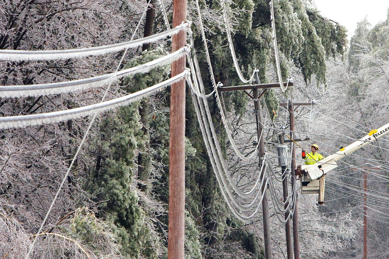 A Central Maine Power worker clears tree limbs off of power lines on Route 202 in Buxton on Friday,